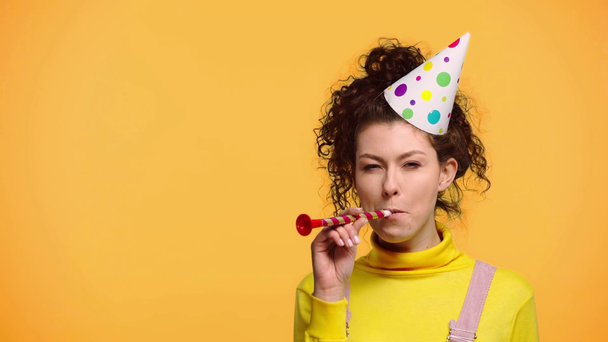 happy woman blowing in party blower isolated on orange - Footage, Video
