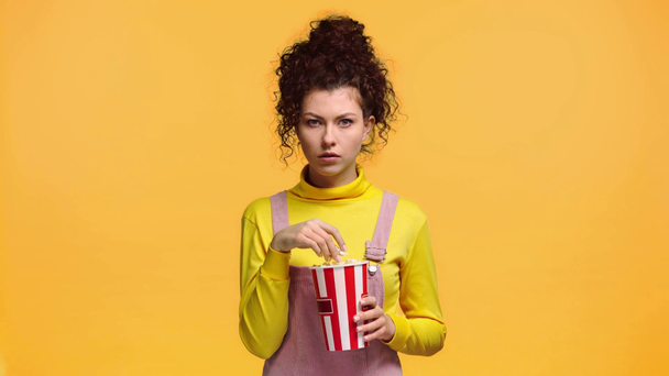 woman eating popcorn isolated on orange  - Séquence, vidéo