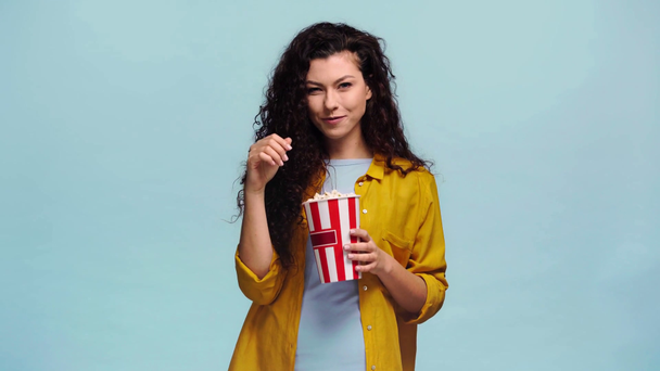 gelukkig vrouw eten popcorn geïsoleerd op blauw  - Video
