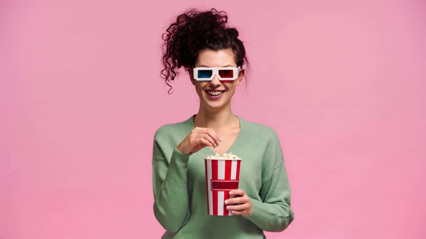 happy girl in 3d glasses eating popcorn isolated on pink  - Materiaali, video