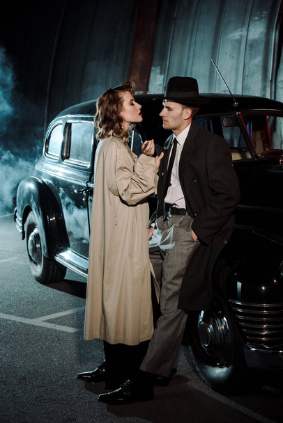 beautiful woman standing near handsome gangster and retro car  - Photo, Image