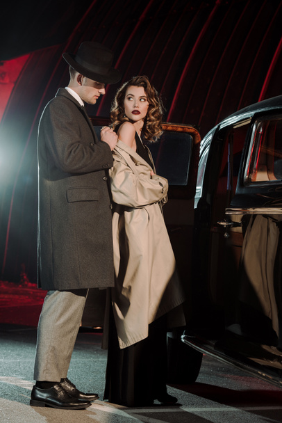 handsome man in hat wearing coat on attractive woman near retro car  - Foto, Imagem