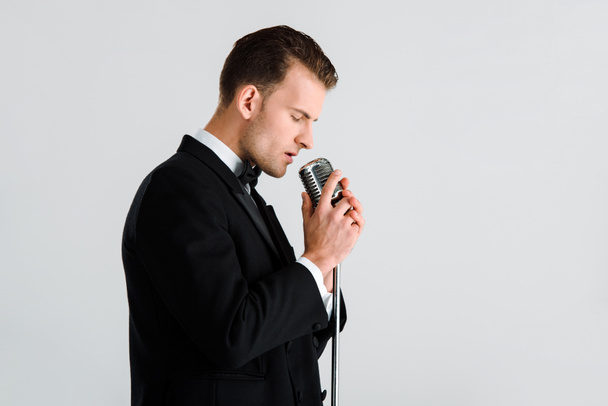 jóképű énekes megérinti retro mikrofon elszigetelt fehér  - Fotó, kép