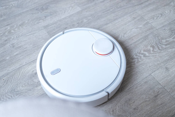 Robotic vacuum cleaner on the floor cleaning the room. Smart cleaning technology. - 写真・画像