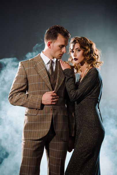 attractive woman standing with handsome gangster on black with smoke  - Fotografie, Obrázek