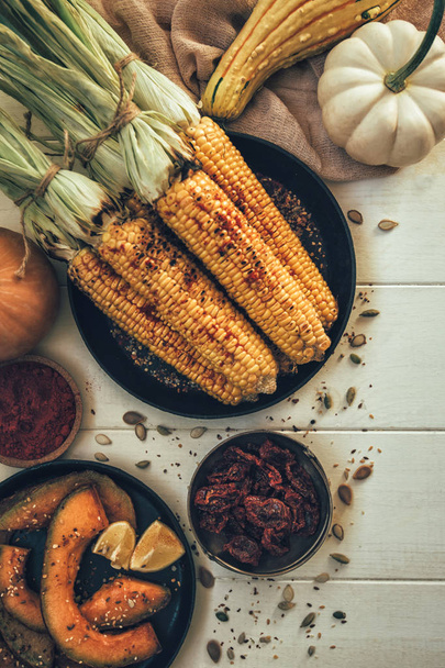 Fall healthy cooking background. Thanksgiving day grilled dinner. Flat-lay of corn cob, baked pumpkins, spice and fresh farm vegetablesover wooden table, top view. - Fotografie, Obrázek