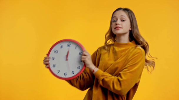 uśmiechnięty nastolatek taniec z zegarem odizolowany na żółty - Materiał filmowy, wideo