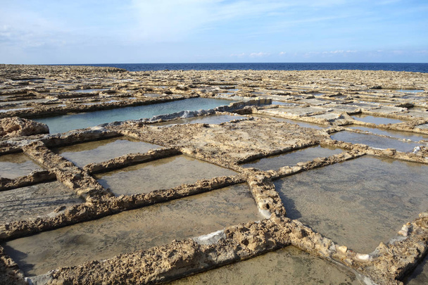 Talerze solne lub mieszkania solne w Xwejni, Zebbug, Gozo, Malta, dawna lokalizacja do produkcji soli, z patelniami solnymi w geometrycznych wzorach nad oceanem - Zdjęcie, obraz