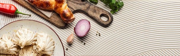 top view of delicious khinkali and adjarian khachapuri near vegetables and spices on beige textured background, panoramic shot - Fotografie, Obrázek