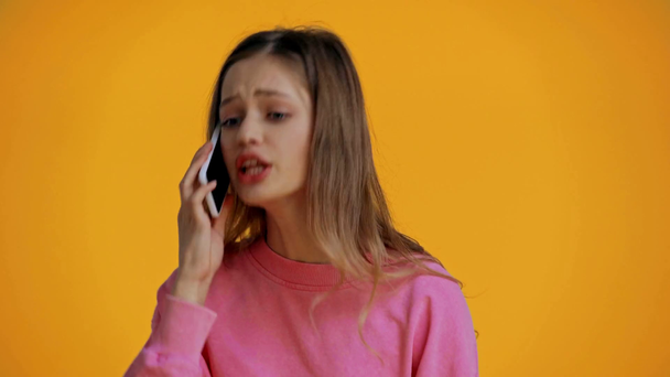 angry teenager talking on smartphone isolated on yellow - Video, Çekim