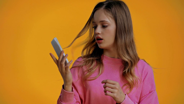 Irritierter Teenager redet auf Smartphone isoliert auf gelb  - Filmmaterial, Video