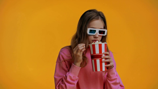 nastolatek oglądanie film i jedzenie popcorn izolowane na żółty - Materiał filmowy, wideo