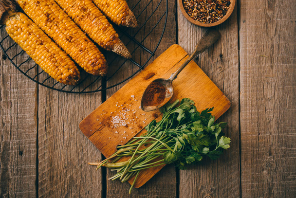 Grilled corn cobs with spice, garlic, lemon, paprika and cheese. Mexican food. Healthy, organic, homemade food. Toned image. Flat lay. - Photo, image