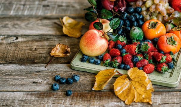 Fresh fruits. Assorted fruits colorful background. Organic food. Fresh raw fruits, berries and fall leaves. Autnum harvest. Flat lay. Copy space. - Photo, image