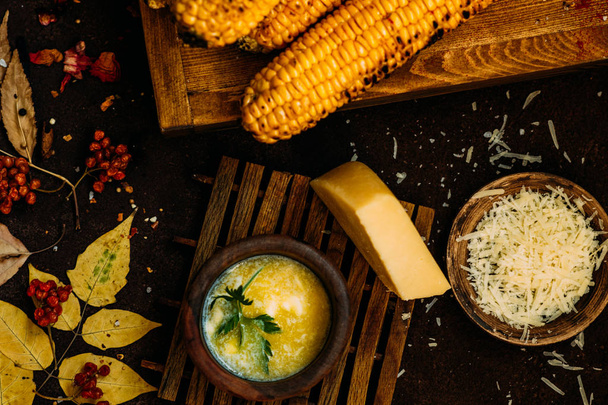 Corn grilled with cheese and spices on the dark rustic background. Autumn food background. Fast food in the summer or fall. Toned image. Flat lay. - Foto, afbeelding