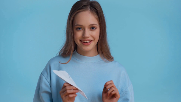 smiling teenager playing with paper plane isolated on blue - Footage, Video