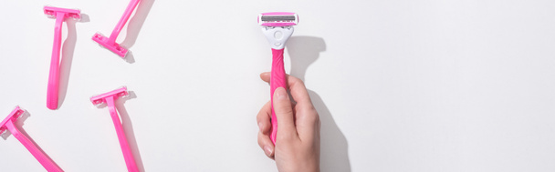 cropped view of woman holding female pink razor on white background, panoramic shot - Фото, зображення