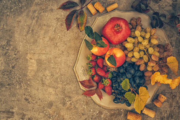 Composition with assorted raw organic fruits. Detox diet. Apples, pomegranate, grapes with autumn yellow leaves on a vintage tray. Flat lay with copy space. - Fotografie, Obrázek