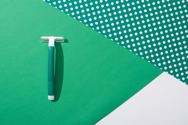 vista superior de la afeitadora desechable verde sobre fondo punteado verde
 - Foto, Imagen