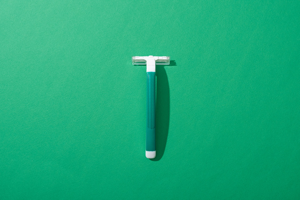 top view of green disposable razor on green background - Foto, Bild