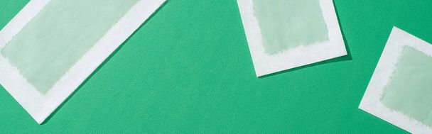 top view of depilation wax stripes on green background, panoramic shot - Foto, Imagem