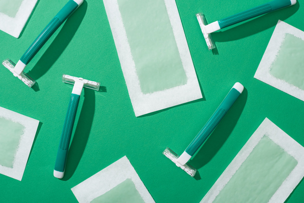 top view of green disposable razors and depilation wax stripes on green background - Foto, immagini