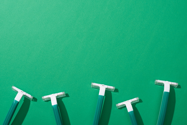vista superior de maquinillas de afeitar desechables verdes sobre fondo verde
 - Foto, imagen