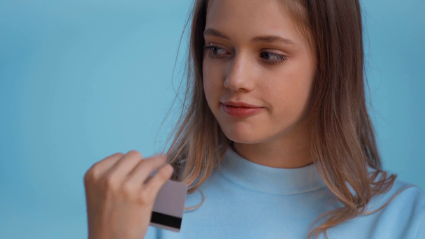 pensativo adolescente sosteniendo tarjeta de crédito aislado en azul
 - Imágenes, Vídeo