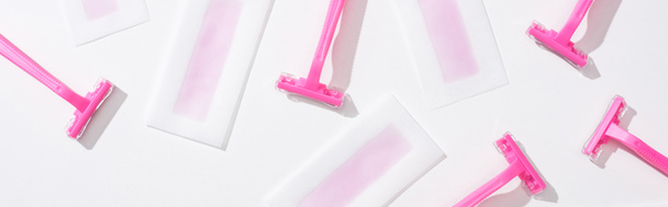 vista superior de lâminas de barbear rosa e listras de cera de depilação no fundo branco, tiro panorâmico
 - Foto, Imagem