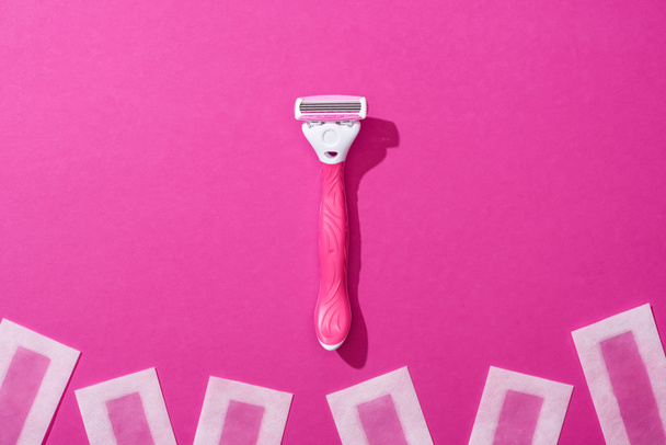 vista superior de la máquina de afeitar femenina y rayas de cera depilación sobre fondo rosa
 - Foto, Imagen