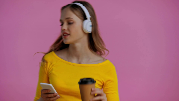teenager pití kávy a poslech hudby izolované na růžové - Záběry, video