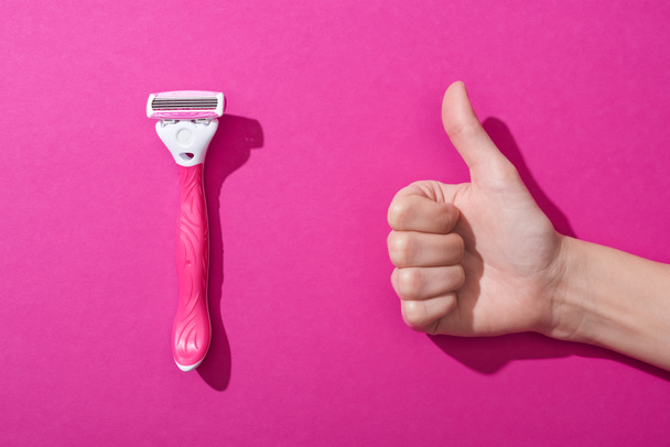 cropped view of woman showing thumb up near razor on pink background - Photo, Image