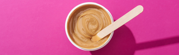 top view of depilation wax in cup with stick on pink background, panoramic shot - Photo, Image