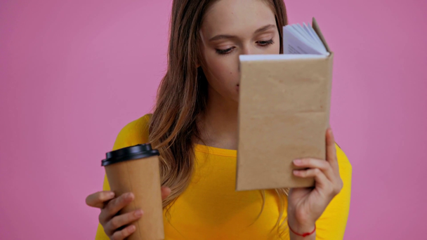 tiener drinken koffie en lezen boek geïsoleerd op roze - Video