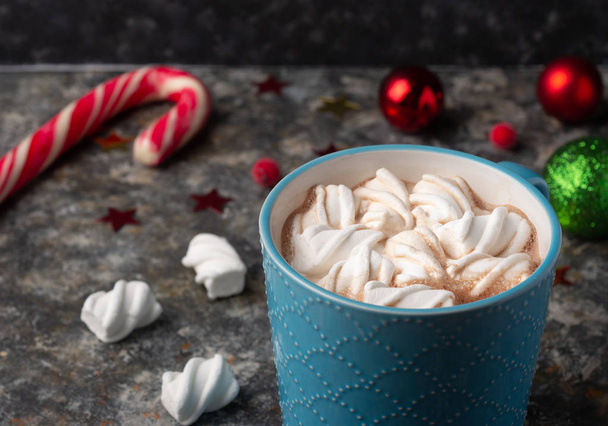 Рождественская и новогодняя уютная праздничная композиция с кружками с какао или шоколадом, зефиром и красной ягодой на темном фоне
.  - Фото, изображение