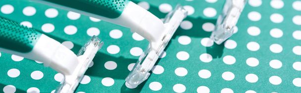 close up view of disposable razors on green and white dotted background, panoramic shot - Zdjęcie, obraz