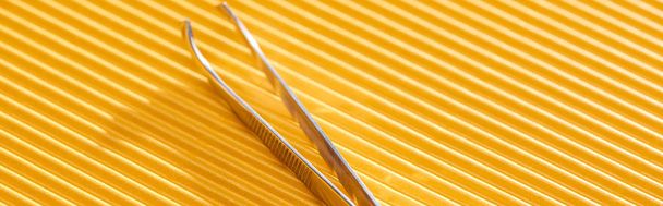 stainless steel tweezers on yellow textured background, panoramic shot - Photo, Image