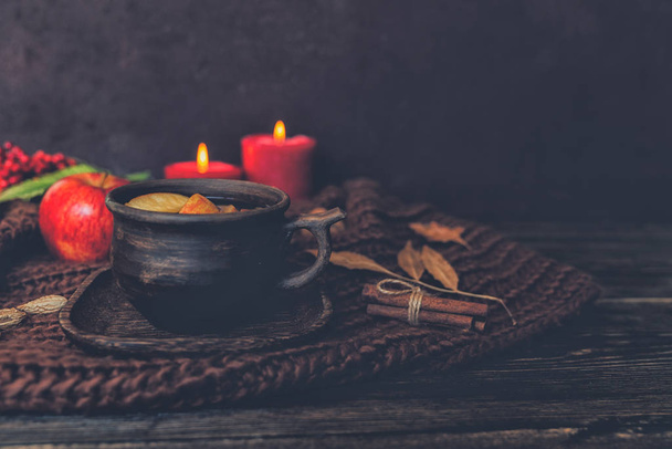 Fall leaves, hot cup of tea, knitted blanket, red berries, candles on wooden table background. Seasonal, autumnal hot drink. Autumn relaxing and still life concept. Toned image. Selective focus. - Foto, Bild