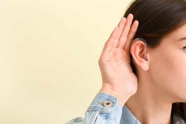Fiatal nő hallókészülék színes háttér - Fotó, kép