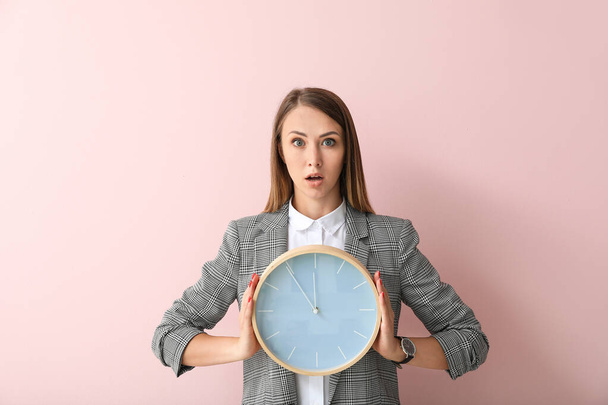 gestreste jonge zakenvrouw met klok op kleur achtergrond - Foto, afbeelding