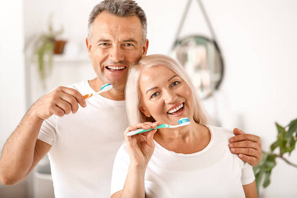 Volwassen paar poetsen tanden thuis - Foto, afbeelding
