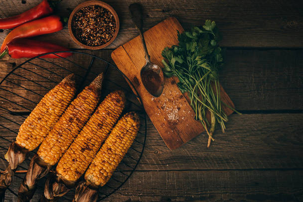 Summer or autumn food background. Ideas for barbecue and grill parties. Grilled corn, cheese on a dark wooden table. Healthy food, organic, bio, homemade food. Top view. - Foto, Imagem