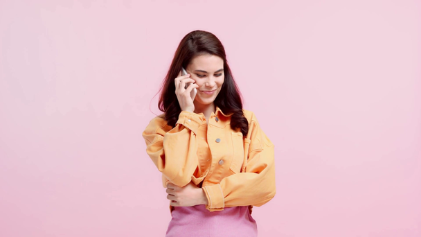 chica sonriente hablando en el teléfono inteligente aislado en rosa
 - Metraje, vídeo