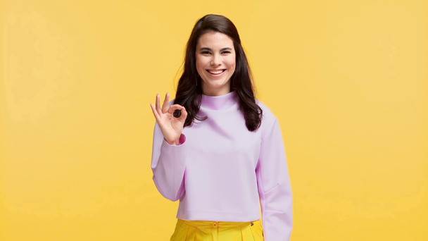 smiling girl nodding head and showing ok sign isolated on yellow - Footage, Video