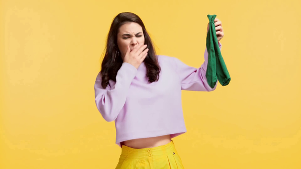 Mädchen riecht Stinkesocken isoliert auf gelb - Filmmaterial, Video