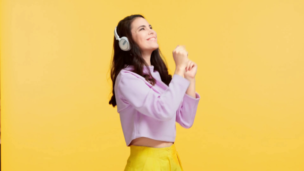 щаслива красива дівчина танцює в навушниках ізольована на жовтому
 - Кадри, відео