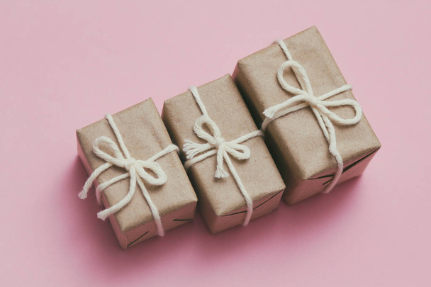 Set of parcels wrapping in brown craft paper and tie hemp string. Package. Delivery service. Online shopping. Your purchase. Gift box on a table. Pink solid background. - Fotó, kép