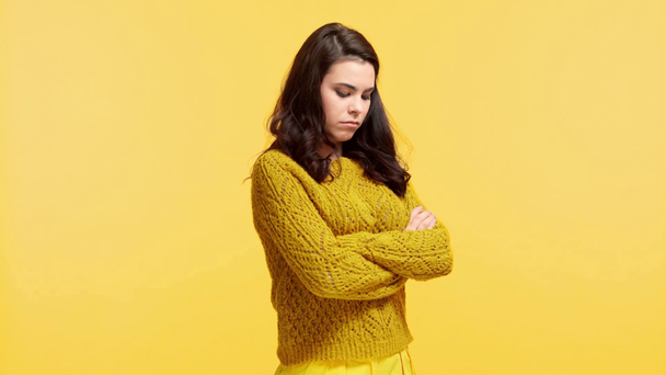 προσβεβλημένο κορίτσι σε πουλόβερ με σταυρωμένα χέρια απομονωμένο σε κίτρινο - Πλάνα, βίντεο