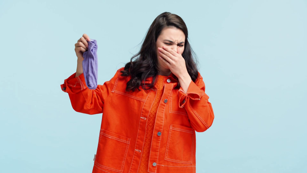 girl smelling stinky socks isolated on blue - Séquence, vidéo