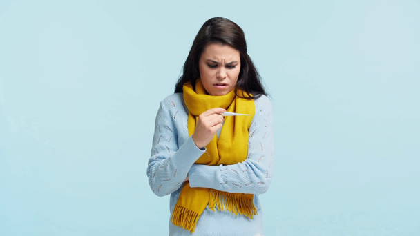 smutna chora dziewczyna w szaliku pomiar temperatury izolowane na niebiesko - Materiał filmowy, wideo